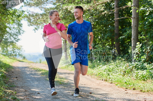 Image of couple enjoying in a healthy lifestyle while jogging on a country road