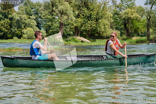 Image of friends are canoeing in a wild river