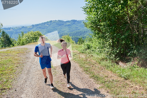 Image of couple enjoying in a healthy lifestyle while jogging on a country road