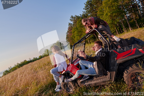 Image of group young happy people enjoying beautiful sunny day while driving a off road buggy car