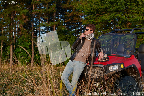 Image of man smoking a cigarette while taking a break from driving a off road buggy car