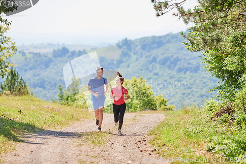 Image of couple enjoying in a healthy lifestyle while jogging on a country road