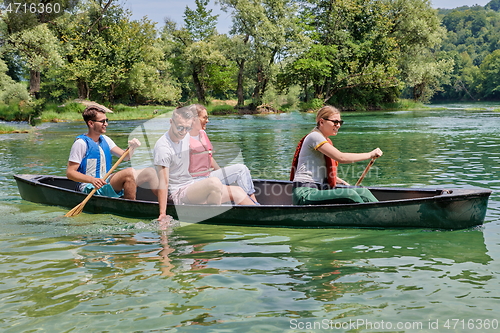 Image of Group adventurous explorer friends are canoeing in a wild river