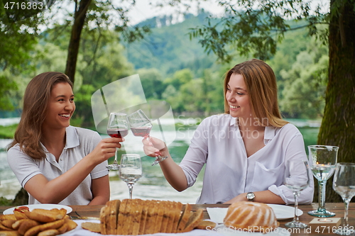 Image of girlfriends having picnic french dinner party outdoor