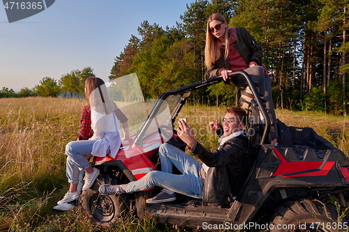 Image of group young happy people enjoying beautiful sunny day while driving a off road buggy car