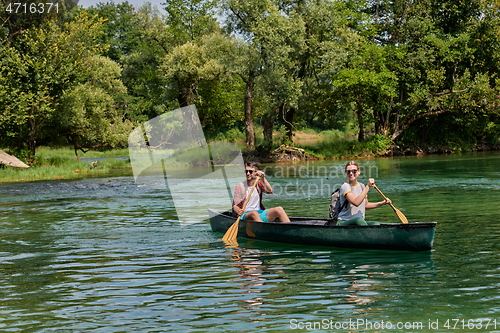 Image of friends are canoeing in a wild river