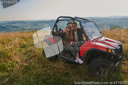 Image of couple enjoying beautiful sunny day taking selfie picture while driving a off road buggy