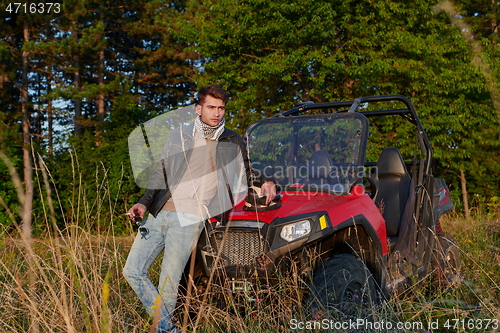 Image of man smoking a cigarette while taking a break from driving a off road buggy car