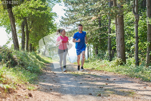 Image of couple enjoying in a healthy lifestyle while jogging on a country road