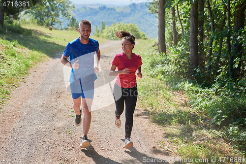 Image of couple enjoying in a healthy lifestyle while jogging on a country road