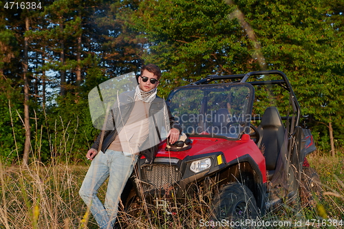 Image of man smoking a cigarette while taking a break from driving a off road buggy car