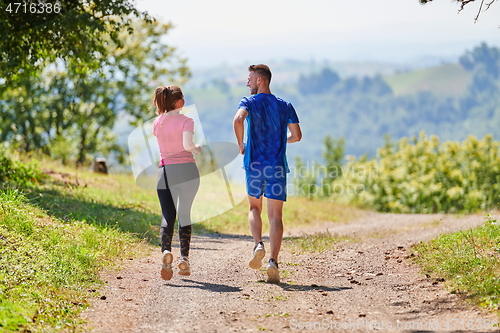 Image of couple enjoying in a healthy lifestyle while jogging on a country road