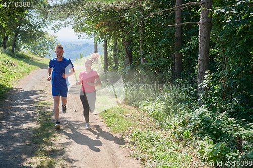 Image of couple enjoying in a healthy lifestyle while jogging on a country road