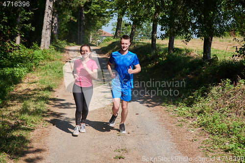 Image of couple enjoying in a healthy lifestyle while jogging on a country road