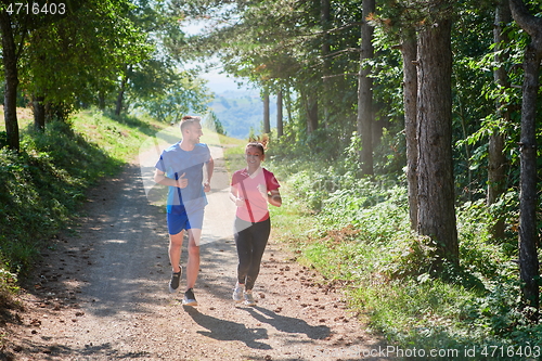 Image of couple enjoying in a healthy lifestyle while jogging on a country road