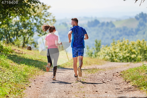 Image of couple enjoying in a healthy lifestyle while jogging on a country road