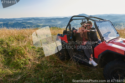 Image of couple enjoying beautiful sunny day taking selfie picture while driving a off road buggy