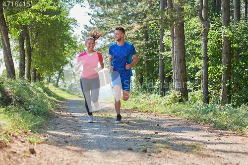 Image of couple enjoying in a healthy lifestyle while jogging on a country road