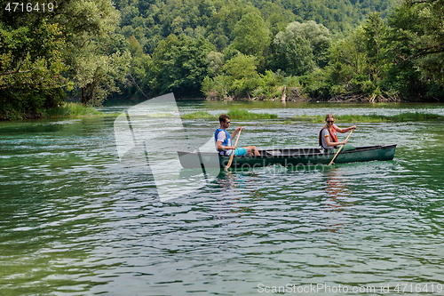 Image of friends are canoeing in a wild river