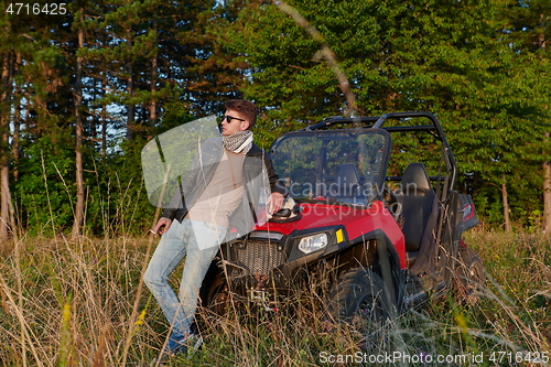 Image of man smoking a cigarette while taking a break from driving a off road buggy car