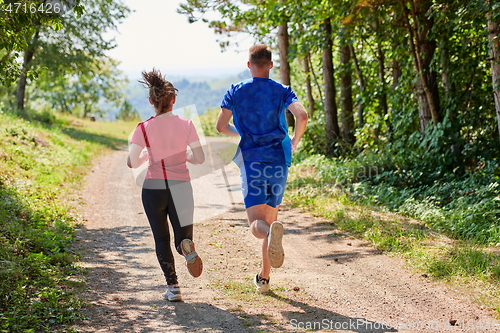 Image of couple enjoying in a healthy lifestyle while jogging on a country road