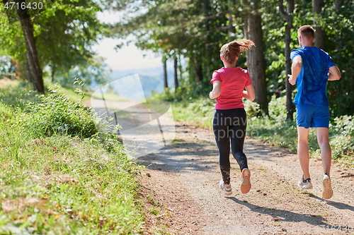 Image of couple enjoying in a healthy lifestyle while jogging on a country road