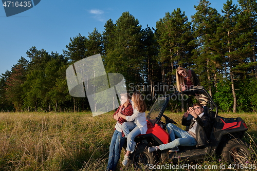 Image of group young happy people enjoying beautiful sunny day while driving a off road buggy car