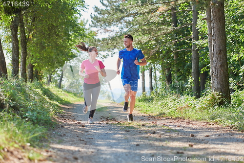 Image of couple enjoying in a healthy lifestyle while jogging on a country road