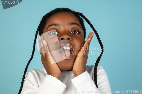 Image of Handsome african little girl portrait isolated on blue studio background with copyspace