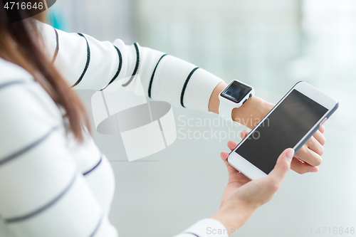 Image of Woman using smart watch connecting with cellphone