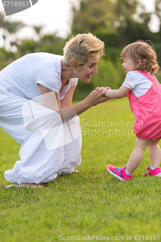 Image of mother and little daughter playing at backyard