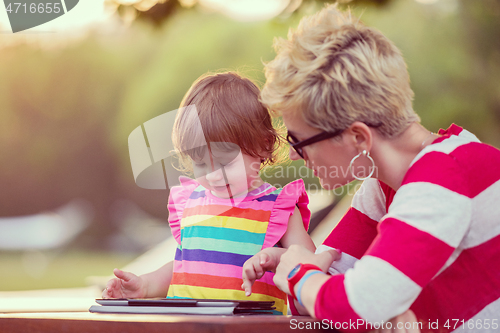 Image of mom and her little daughter using tablet computer