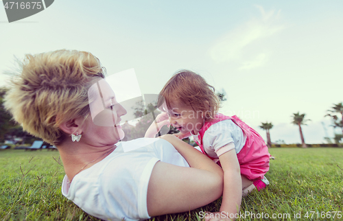 Image of mother and little daughter playing at backyard