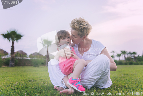 Image of mother and little daughter playing at backyard