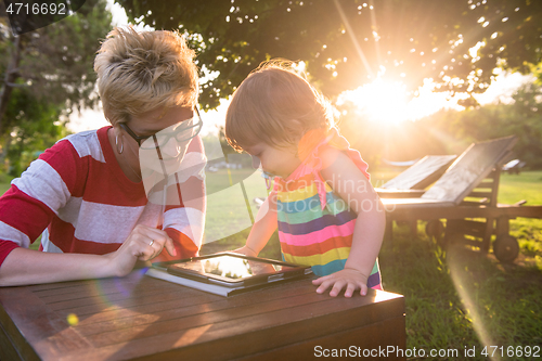 Image of mom and her little daughter using tablet computer