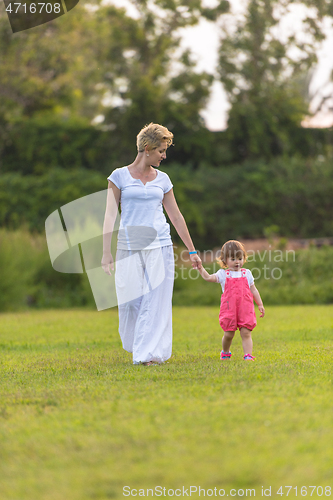 Image of mother and little daughter playing at backyard