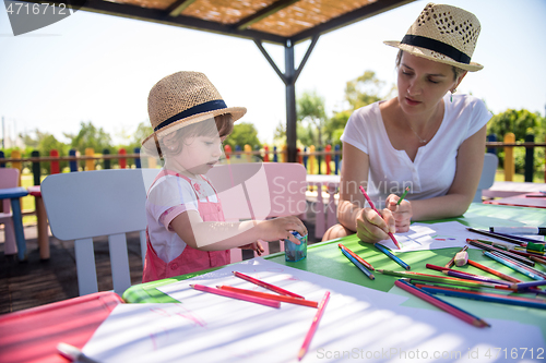 Image of mom and little daughter drawing a colorful pictures