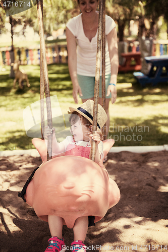 Image of mother and daughter swinging in the park