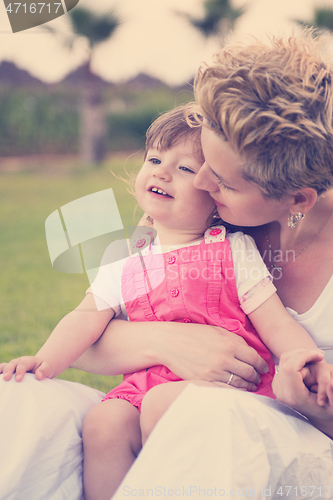 Image of mother and little daughter playing at backyard