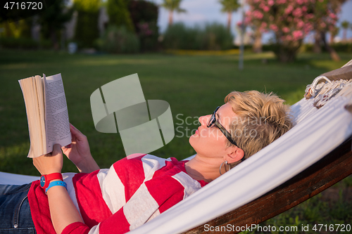 Image of woman reading a book while relaxing on hammock