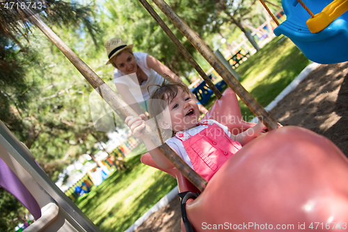 Image of mother and daughter swinging in the park