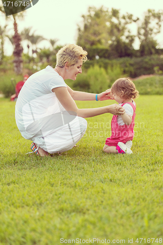 Image of mother and little daughter playing at backyard
