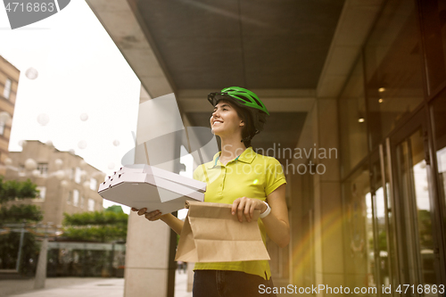 Image of Young woman as a courier delivering pizza using gadgets