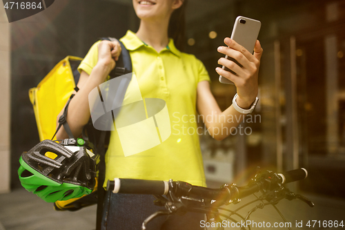 Image of Young woman as a courier delivering food using gadgets