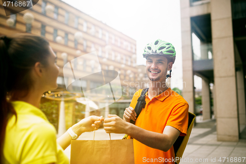 Image of Young man as a courier delivering package using gadgets