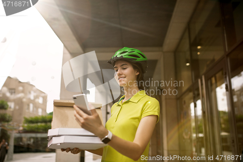 Image of Young woman as a courier delivering pizza using gadgets