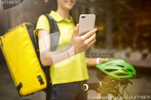 Image of Young woman as a courier delivering food using gadgets