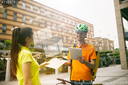 Image of Young man as a courier delivering package using gadgets