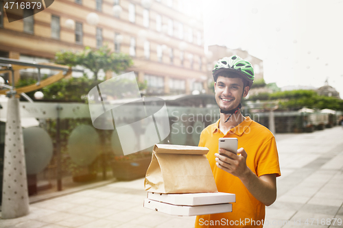 Image of Young man as a courier delivering pizza using gadgets