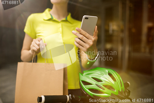 Image of Young woman as a courier delivering package using gadgets